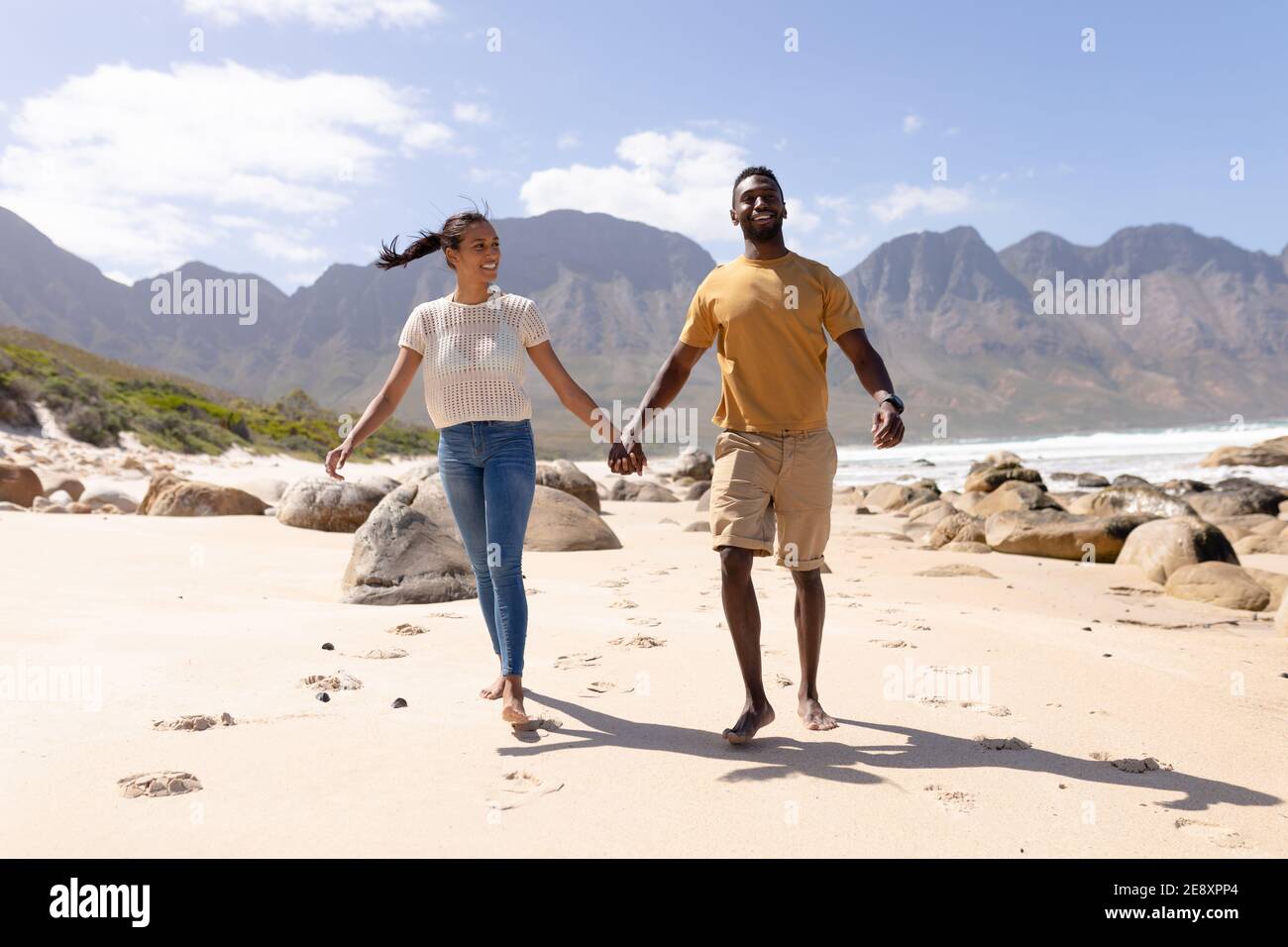 African american couple walking holding hands on a beach by the sea ...
