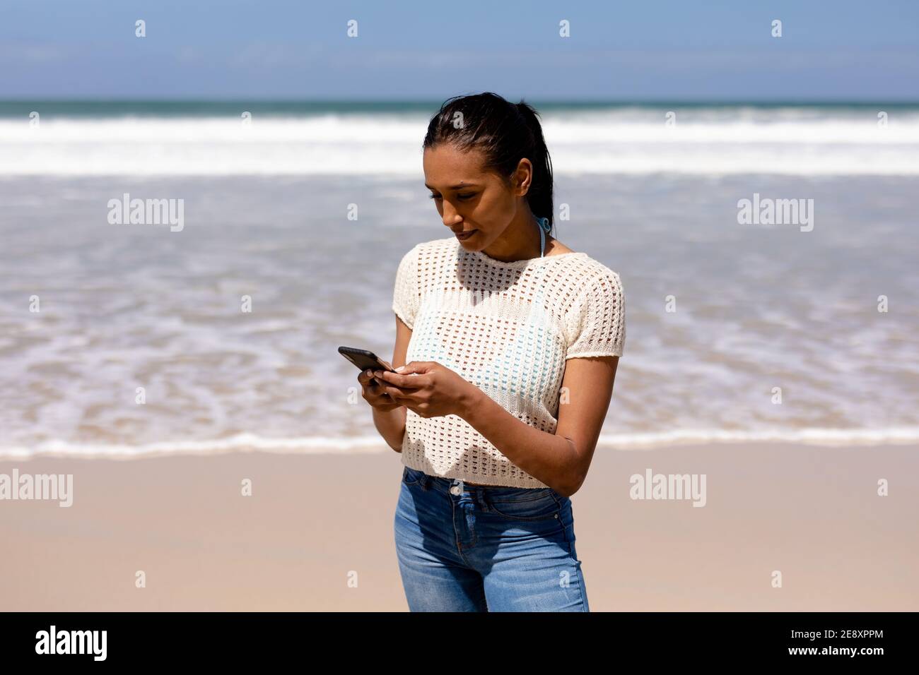 African american woman using smartphone on a beach by the sea Stock ...
