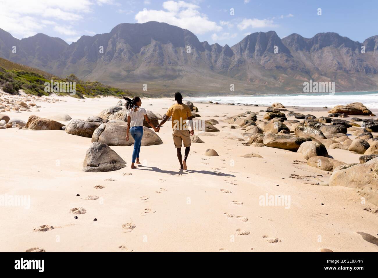 African american couple walking holding hands on a beach by the sea ...