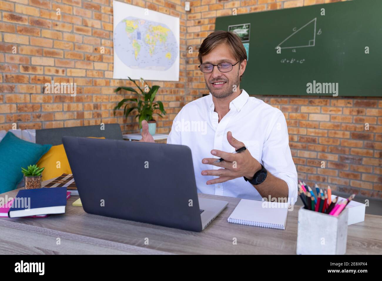 Caucasian male maths teacher giving online lesson sitting at laptop talking Stock Photo