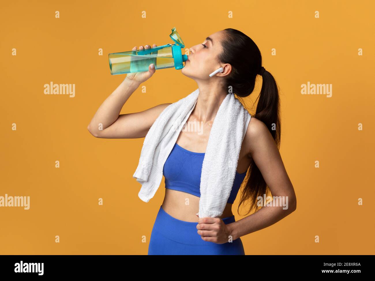 Sporty woman drinking water from bottle at studio Stock Photo - Alamy
