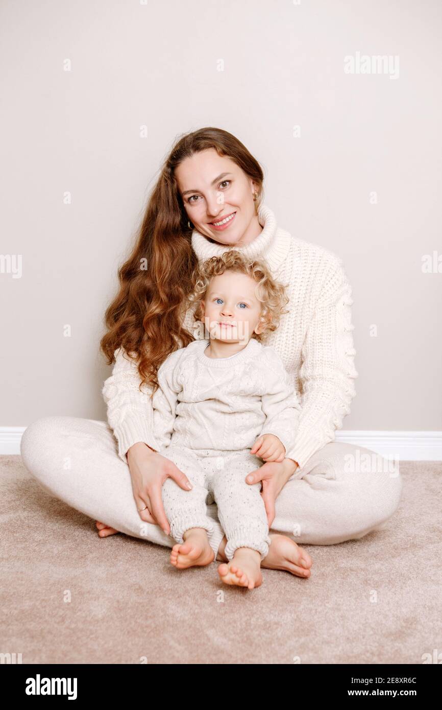 Beautiful smiling young white Caucasian woman mother holding cute adorable curly baby boy child. Authentic candid family lifestyle. Happy motherhood a Stock Photo