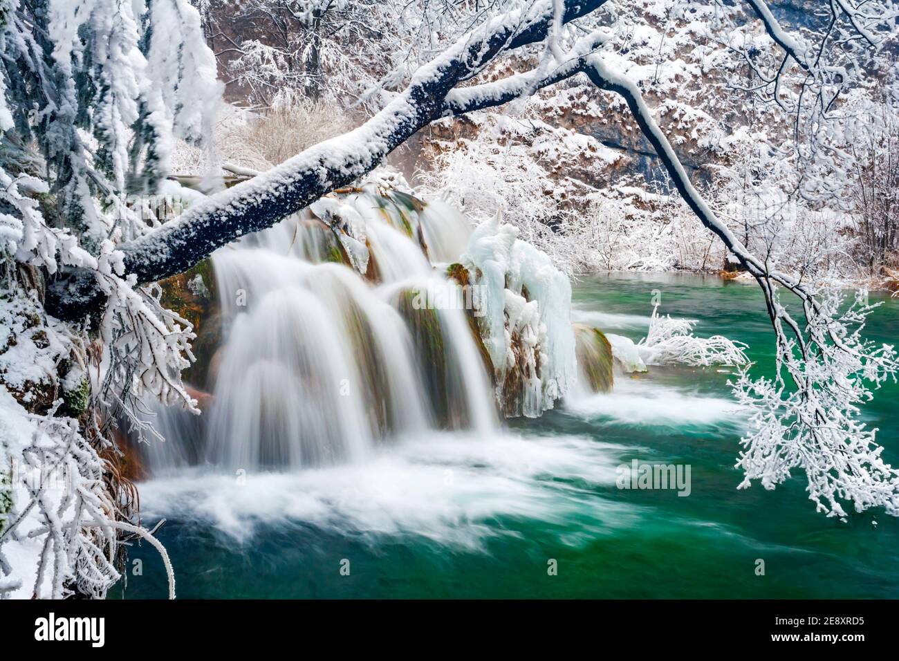 Small waterfall national park Plitvice lakes Croatia Europe Winter under covered cover snow ice long exposure tripod shot waterflow water flowing flow Stock Photo