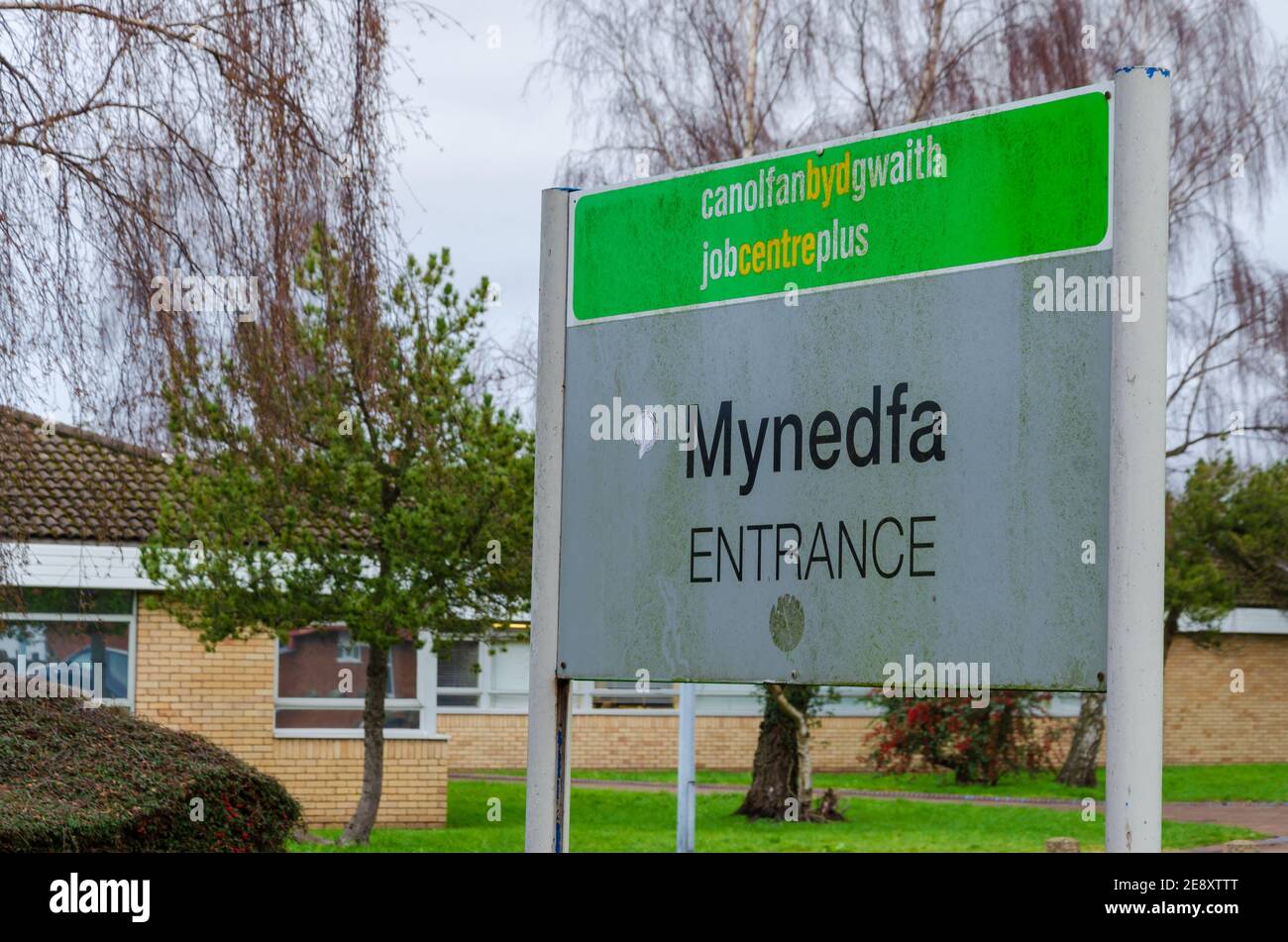 Mold, Flintshire; UK: Jan 28, 2021: A shabby, bilingual sign directs people to the entrance of the job centre Stock Photo