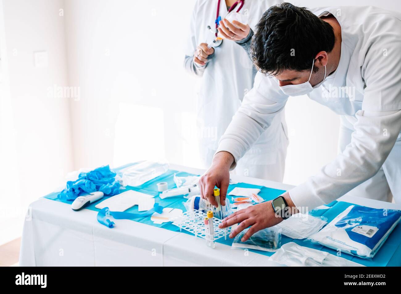 Young male nurse prepares the material for a PCR day on a table with medical supplies Stock Photo