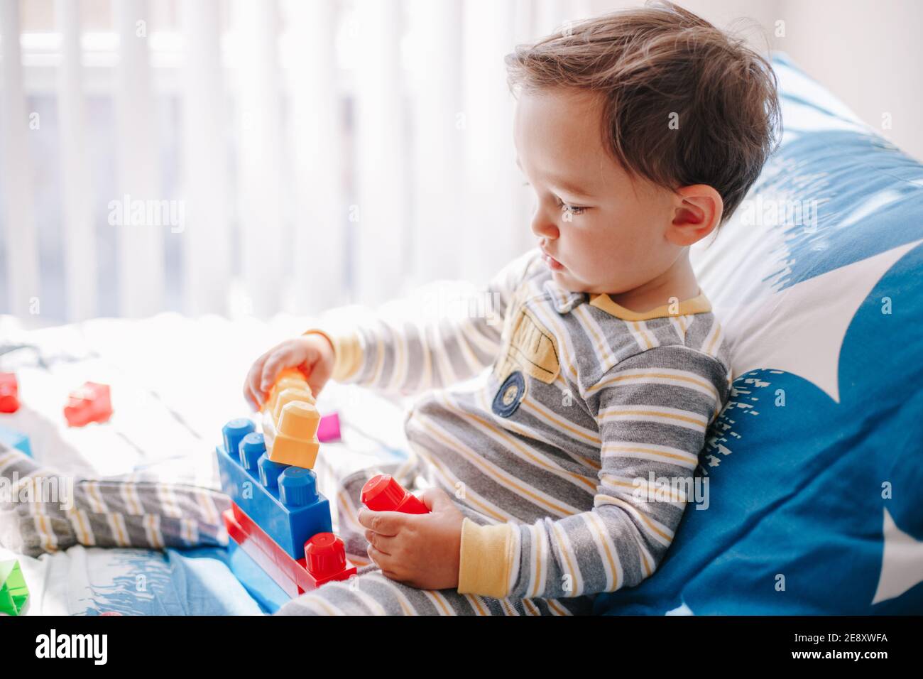 Cute baby toddler playing building with learning toy stacking blocks at