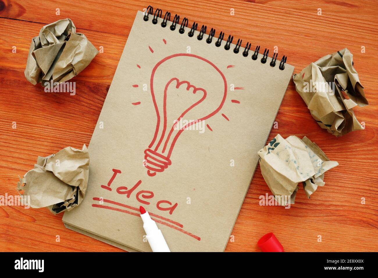 Idea concept. Light bulb as symbol of creativity. Success and sheets of paper after unsuccessful attempts. Stock Photo