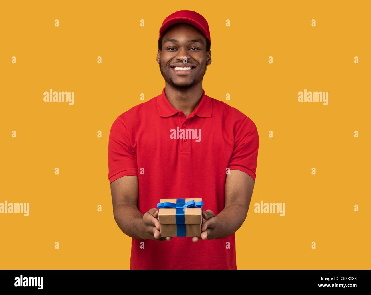 Black delivery guy holding gift box showing it to camera Stock Photo