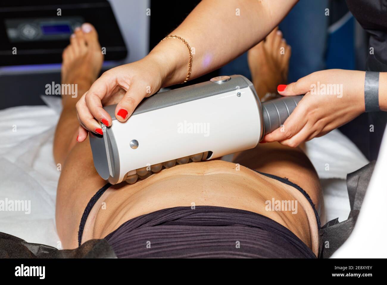 A professional cosmetologist performs an electromagnetic muscle massage on a high-intensity trainer. Stock Photo