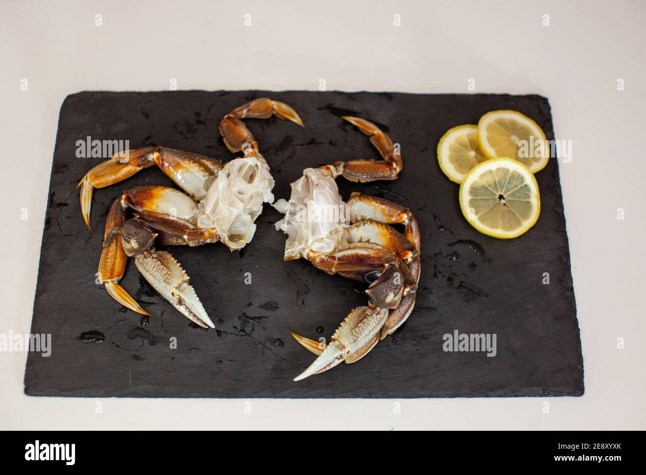 Raw, cleaned, uncooked Dungeness crab legs sit on a platter in the kitchen ready to be cooked for dinner Stock Photo
