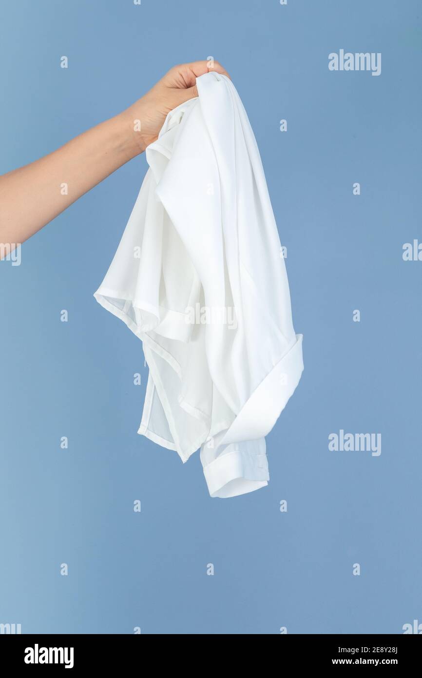 hand holding a white silk textile, blue background empty space for text Stock Photo