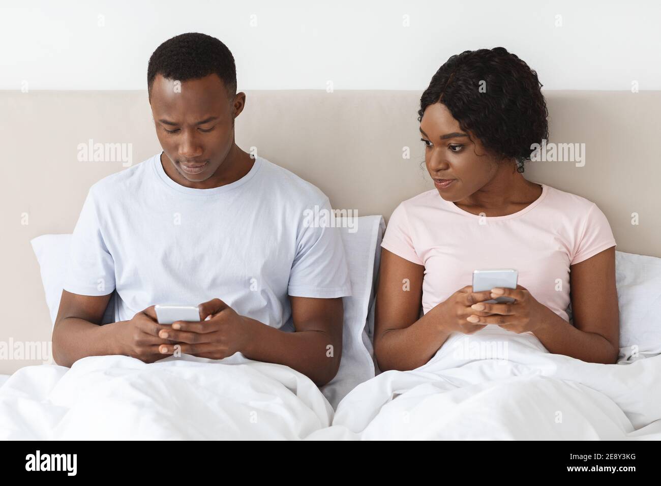 Young black woman eavesdropping on her boyfriend using mobile phone