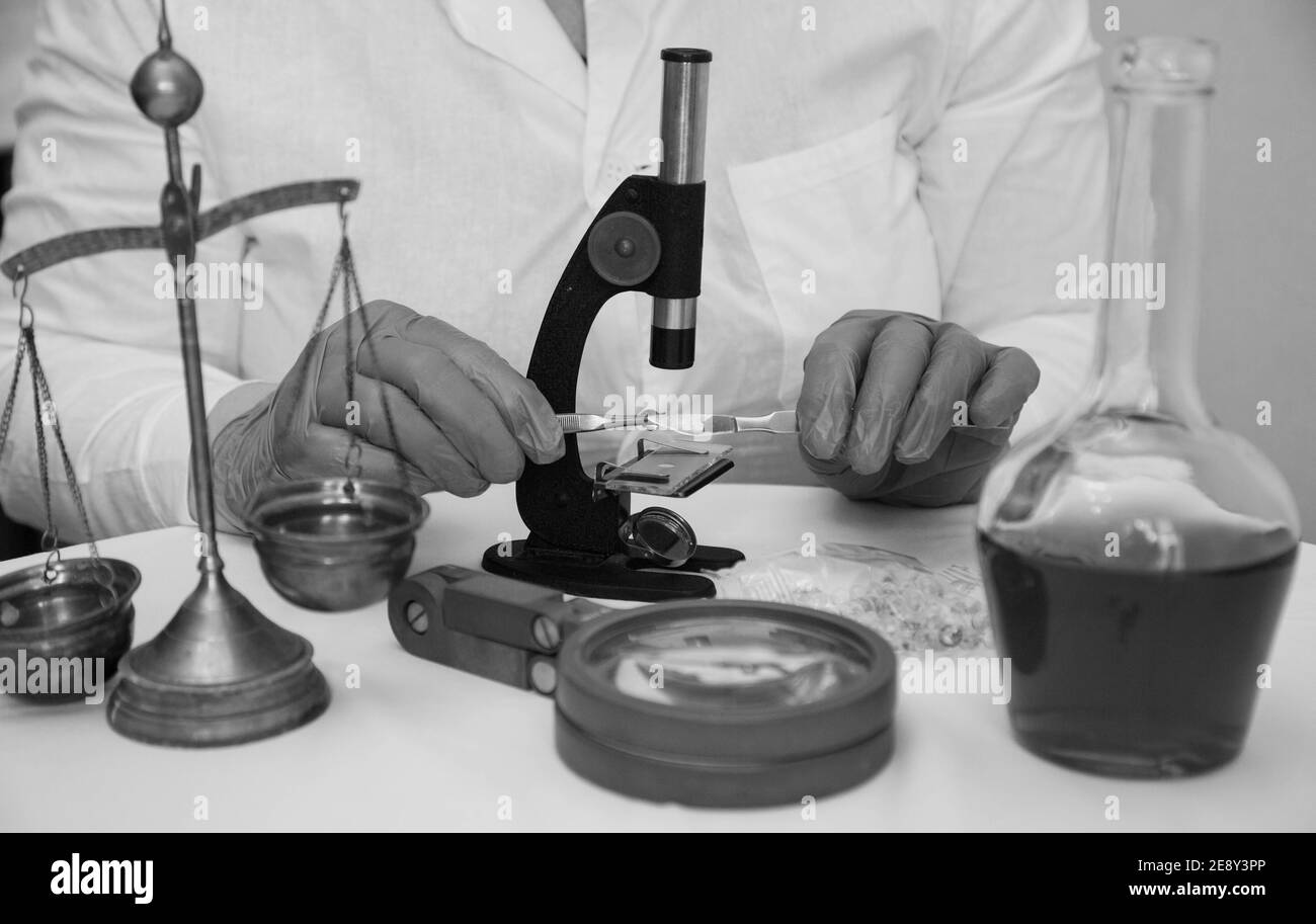 Microscope and hands in lab wear gloves wb Stock Photo