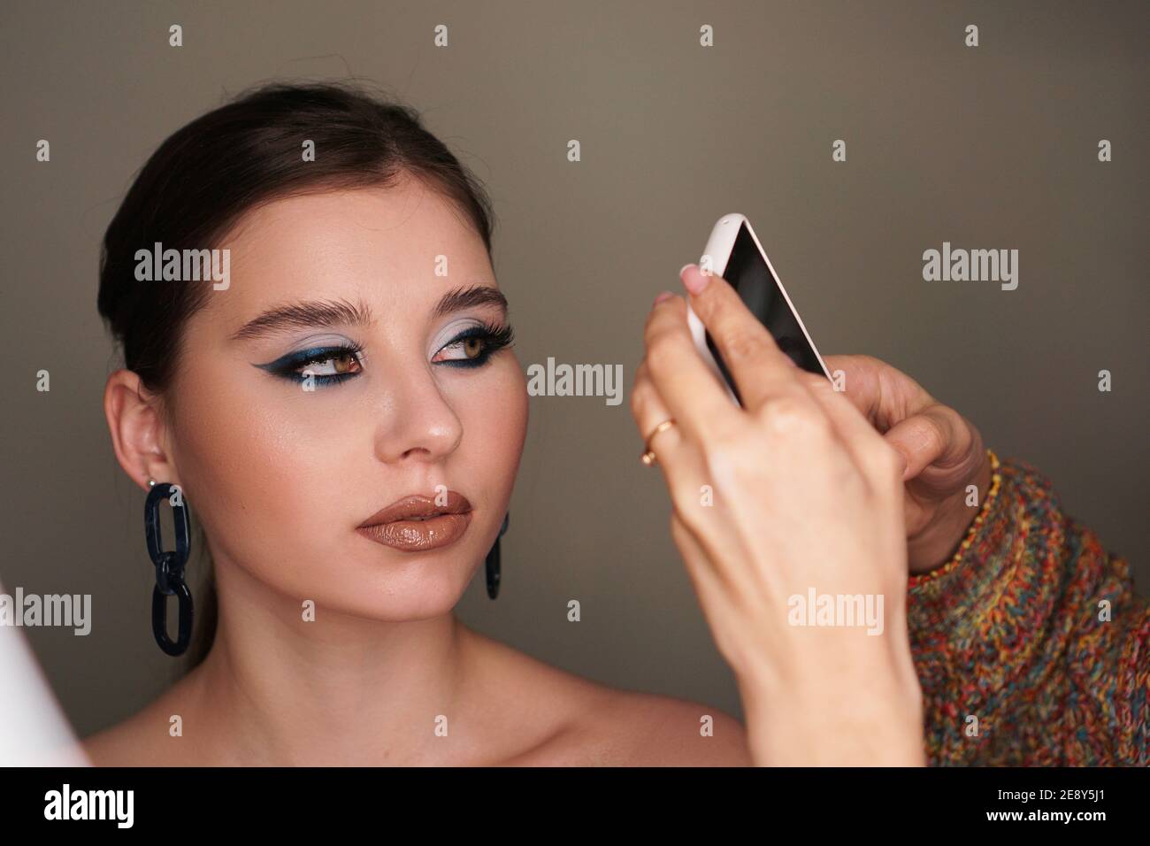 Make up artist taking mobile photo for the model with blue fashion