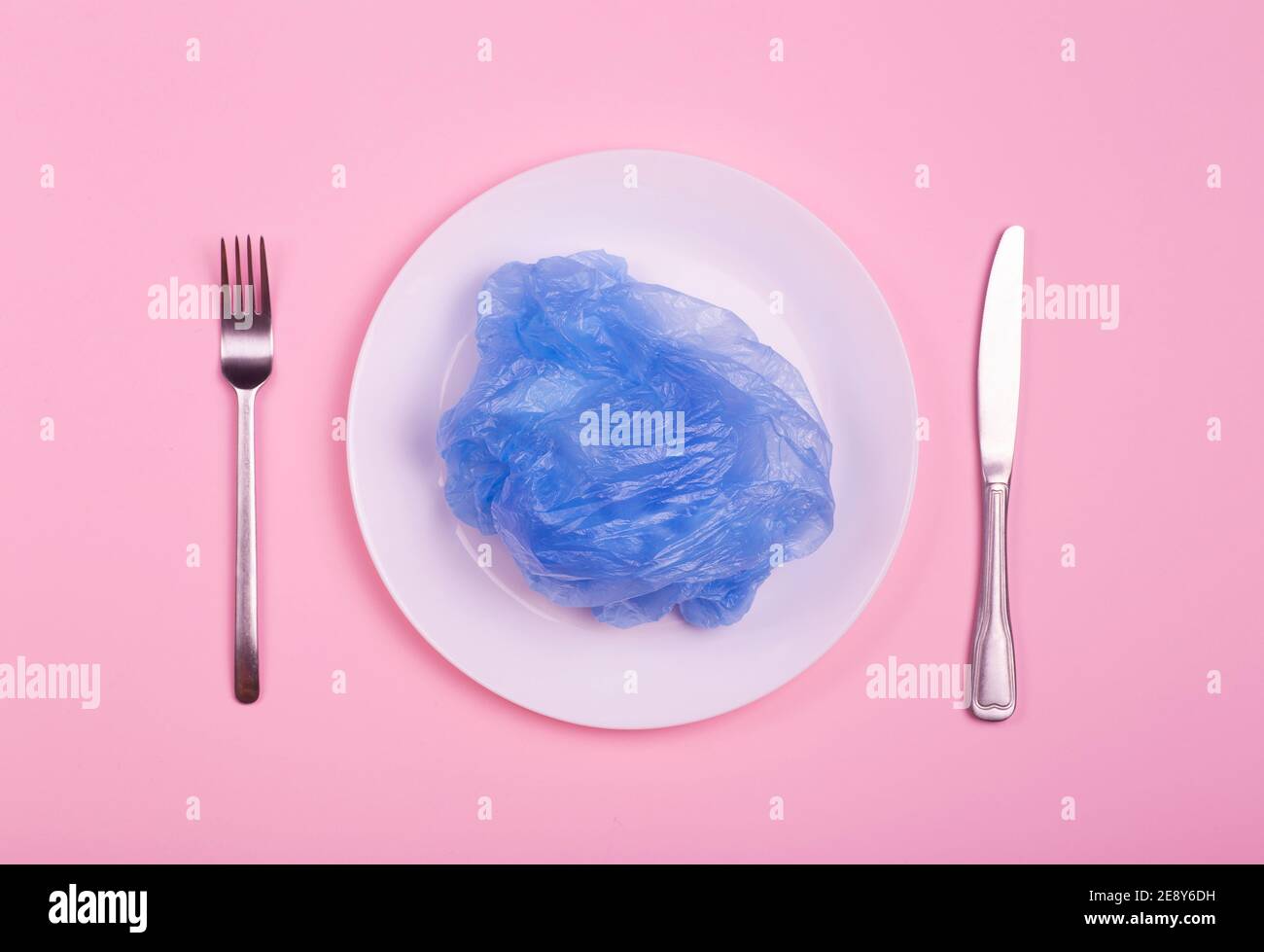 Plastic bag on a plate on a pink background. Nature pollution concept