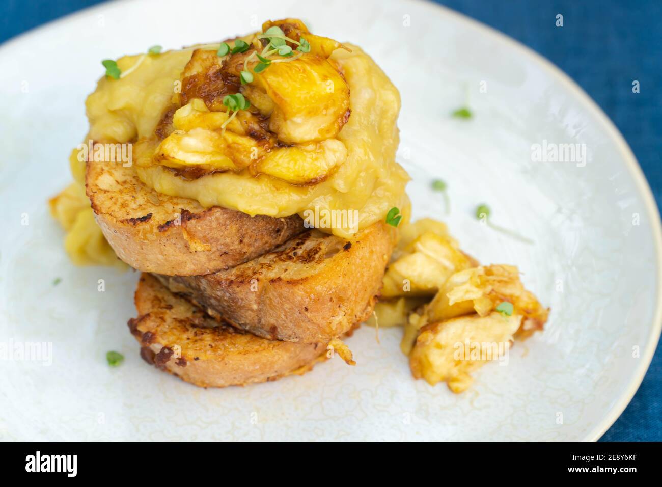Vegan french toasts with peanut butter, syrup and banana on a white