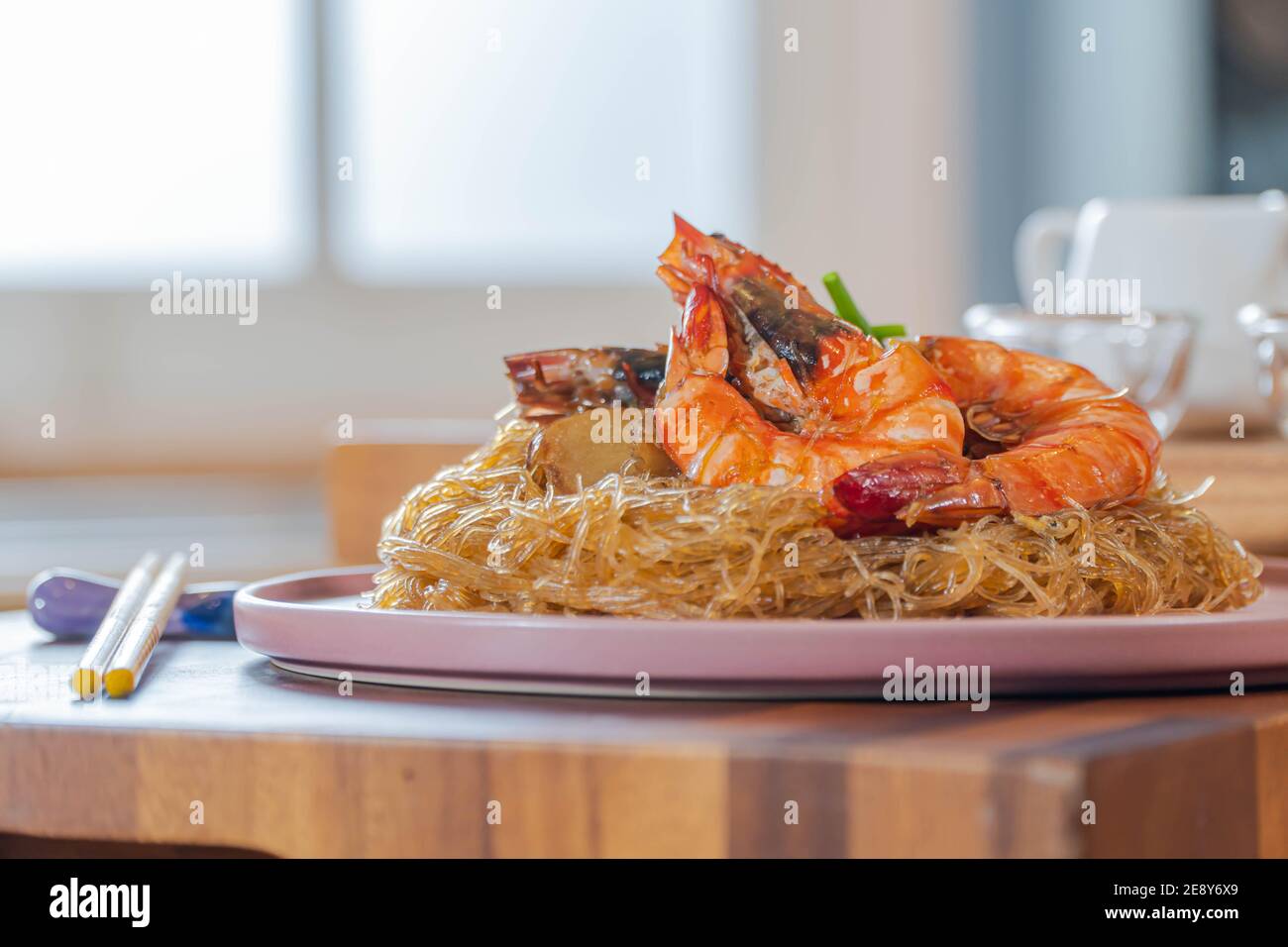 Baked Shrimp with Glass Noodles, a traditional Thai food wrapped in heat-treated freud paper and chopsticks, ready to serve-eat Stock Photo
