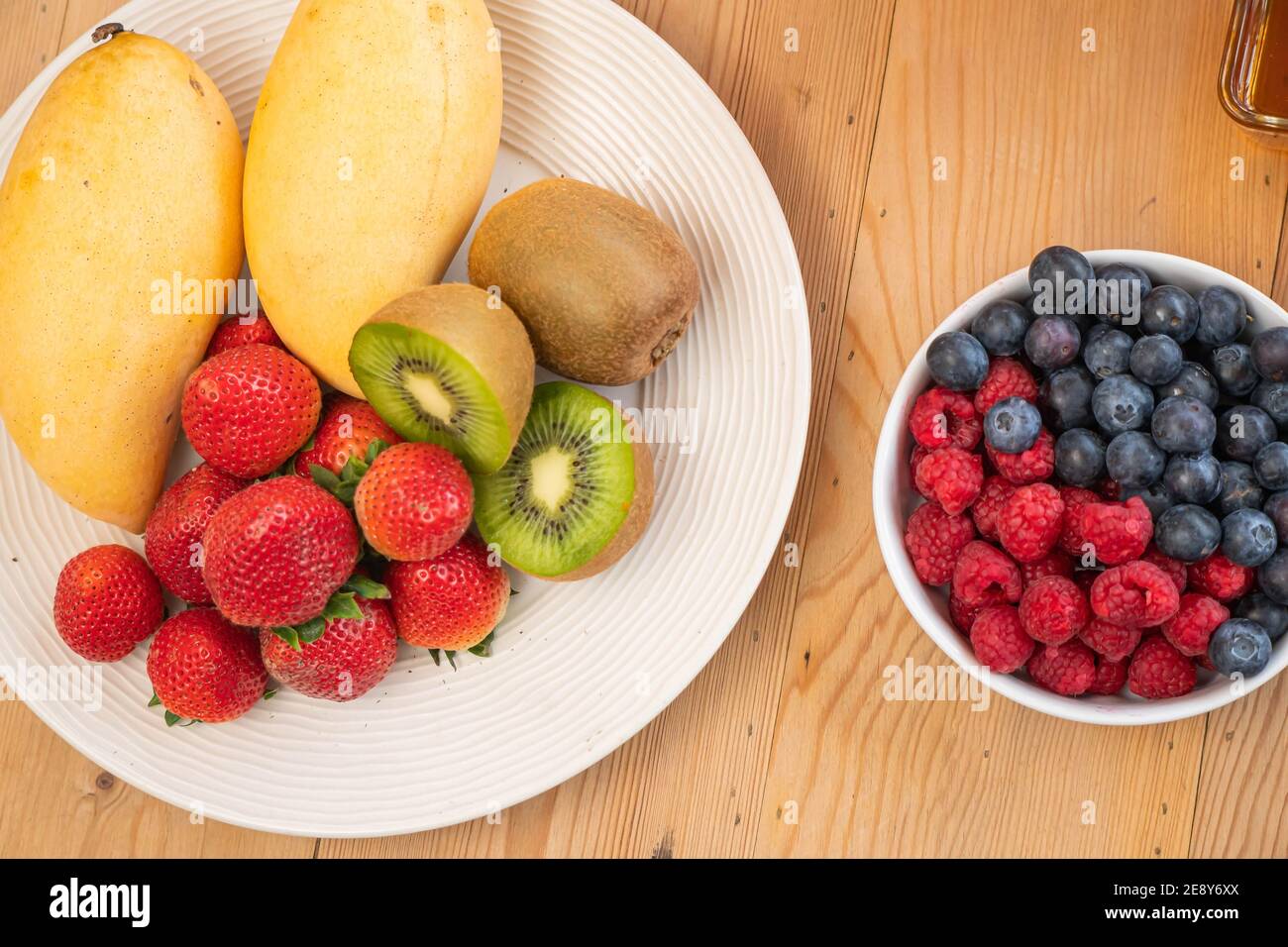 mixed fresh fruits (strawberry, raspberry, blueberry, kiwi, mango) on wood bowl Stock Photo