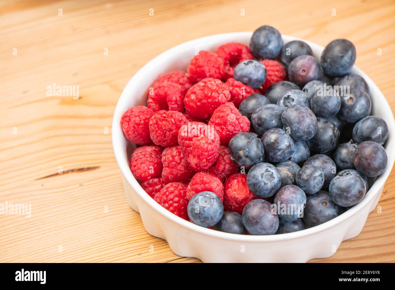 mixed fresh fruits (strawberry, raspberry, blueberry, kiwi, mango) on wood bowl Stock Photo