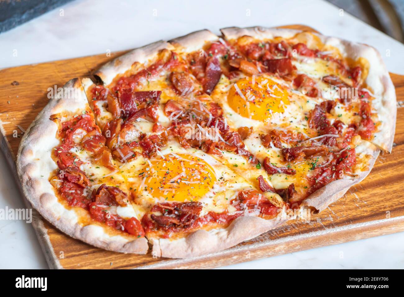 Ham and Eggs Breakfast style pizza on wooden platter Stock Photo