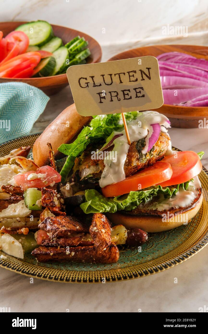 Greek stuffed turkey burger topped with cucumber slices and tzatziki yogurt sauce served with Mediterranean street cart fried potatoes with feta chees Stock Photo