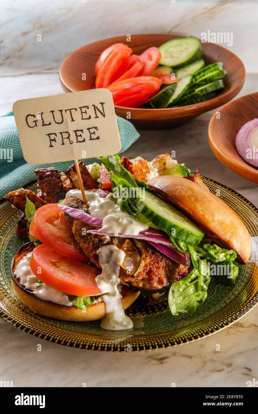 Greek stuffed turkey burger topped with cucumber slices and tzatziki yogurt sauce served with Mediterranean street cart fried potatoes with feta chees Stock Photo