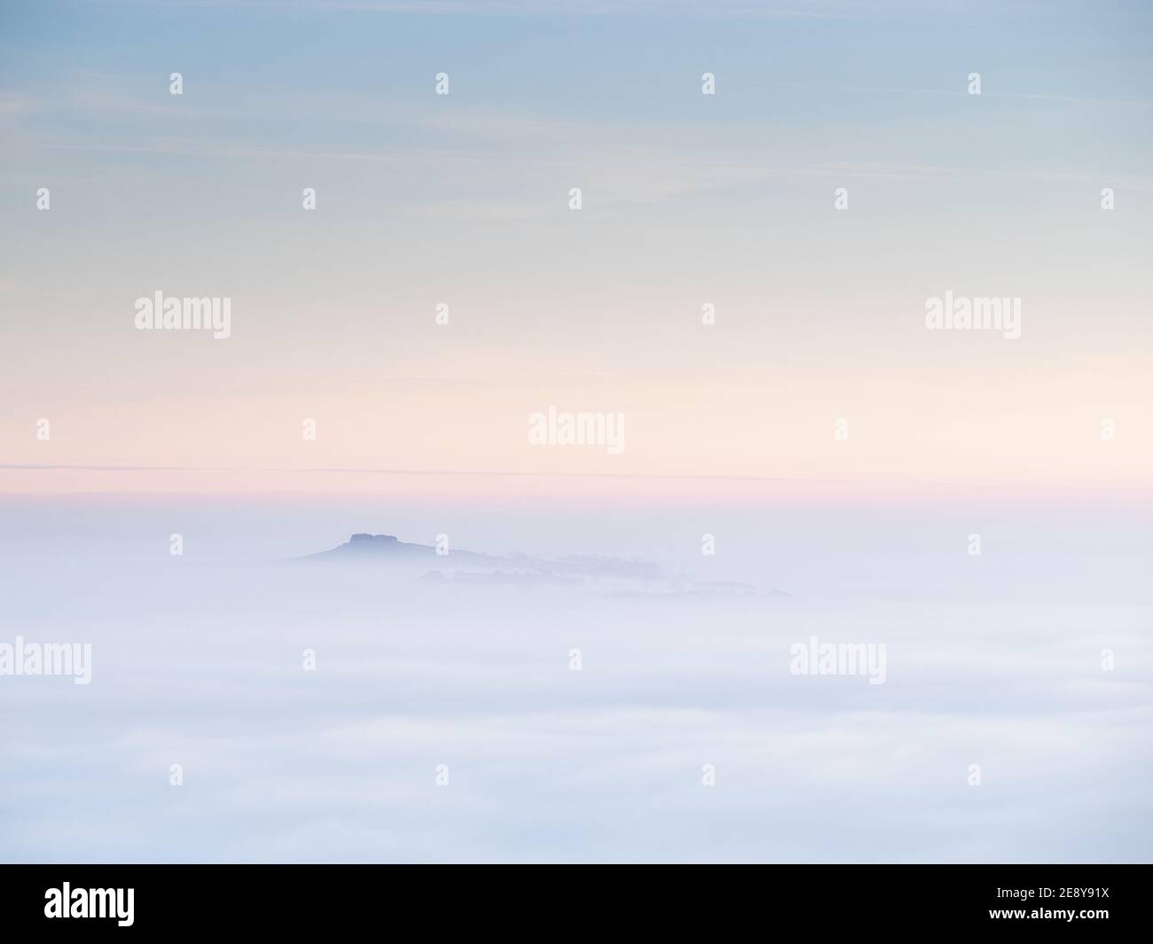 Almscliffe Crag peeks through a sea of fog during an autumn temperature inversion in Lower Wharfedale, with the rest of the landscape obscured. Stock Photo