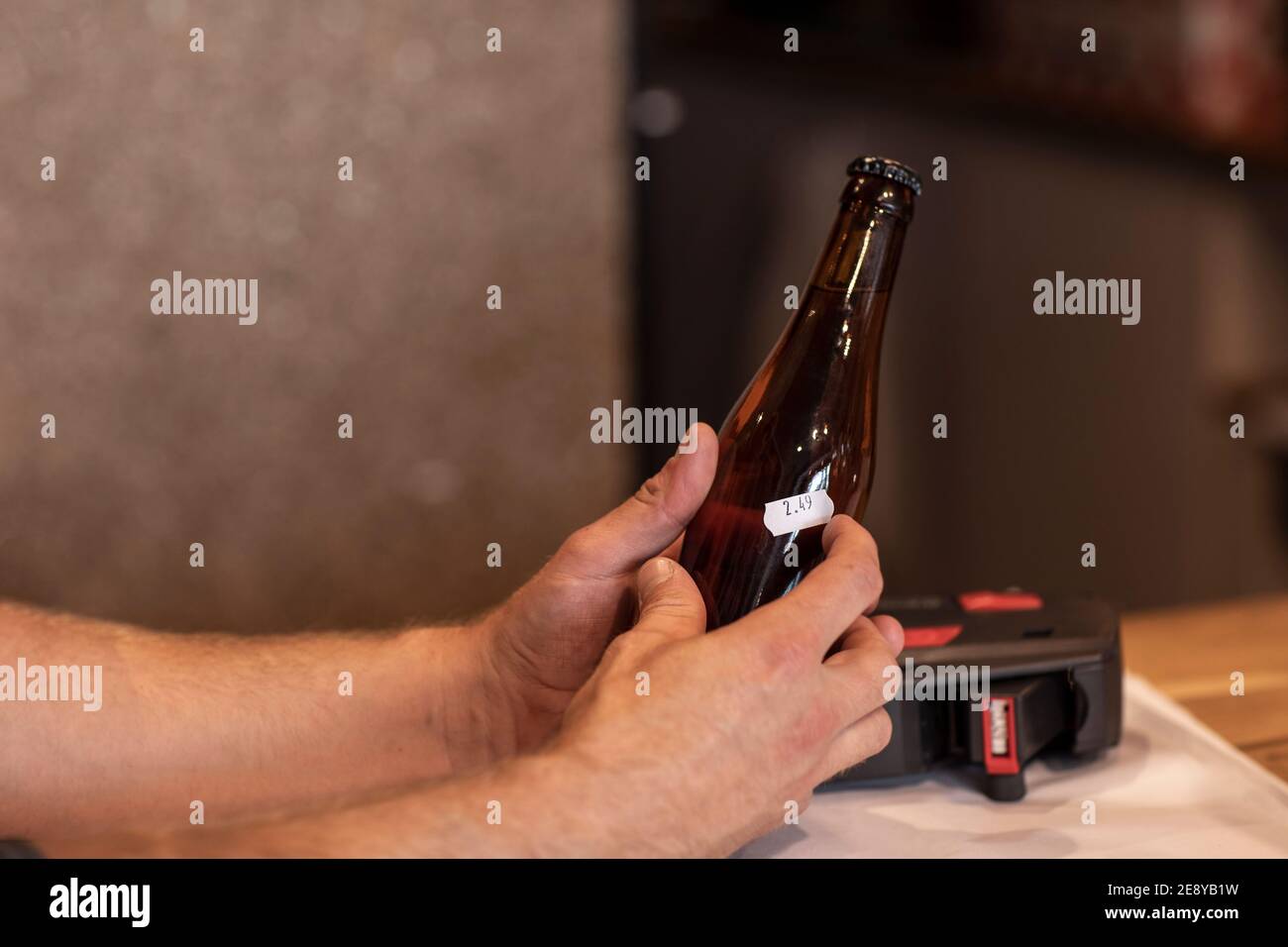 Hands of a man pricing his bottled beers in his store. Selling beer in