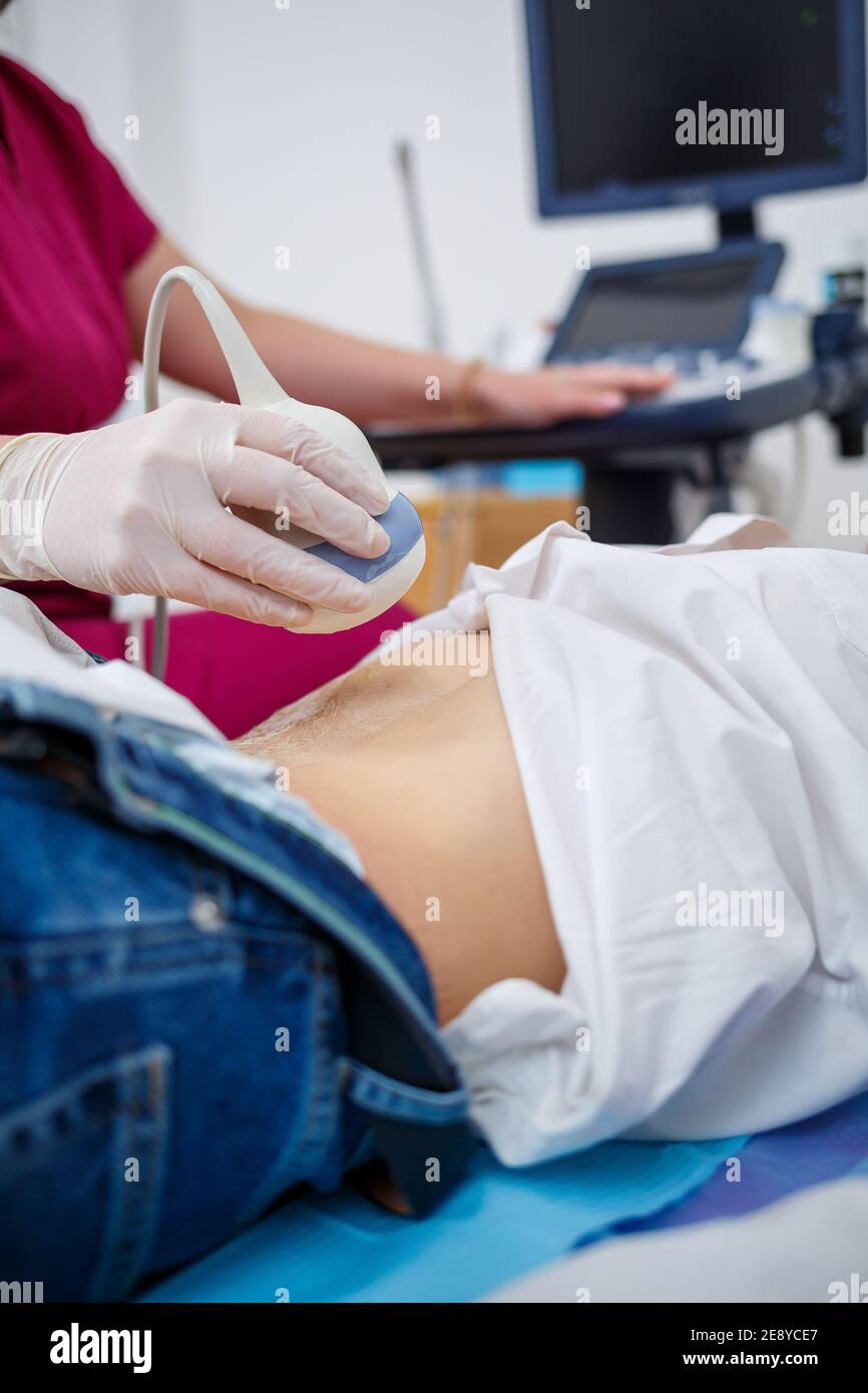 A young woman lies on a couch, a doctor's appointment, an ultrasound scan of the abdominal