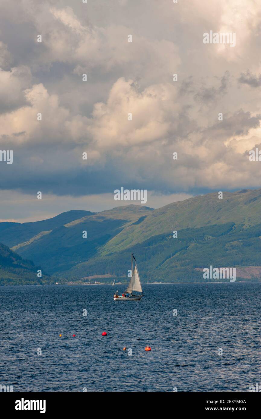 Yacht sailing in the Firth of Clyde off the southern coast at greenock Argyle hills behind. Stock Photo