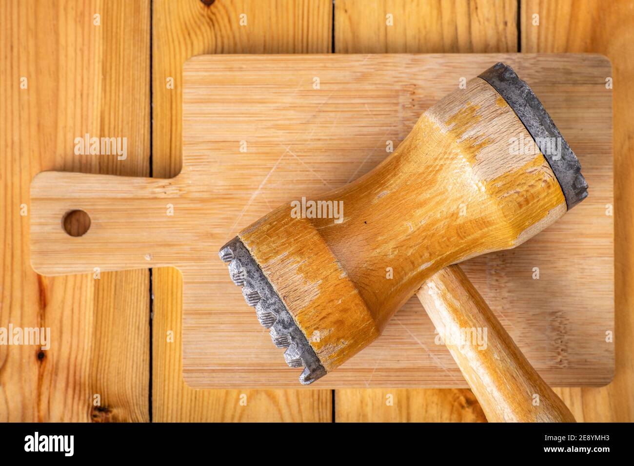 Wooden meat grinder on a chopping board. Wooden kitchen utensils on the kitchen table. Light background. Stock Photo