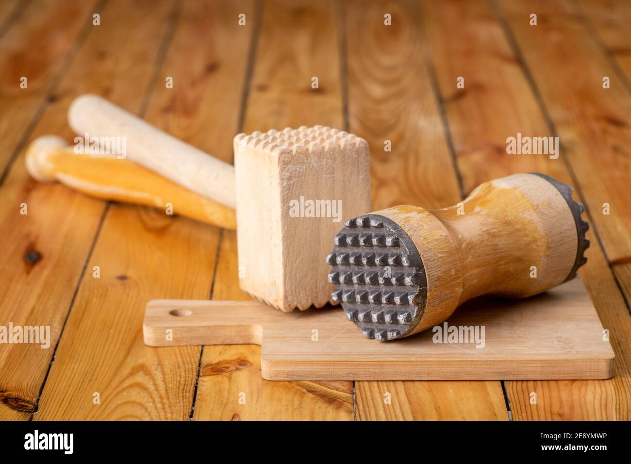 Wooden meat mashers. Wooden kitchen utensils on the kitchen table. Light background. Stock Photo