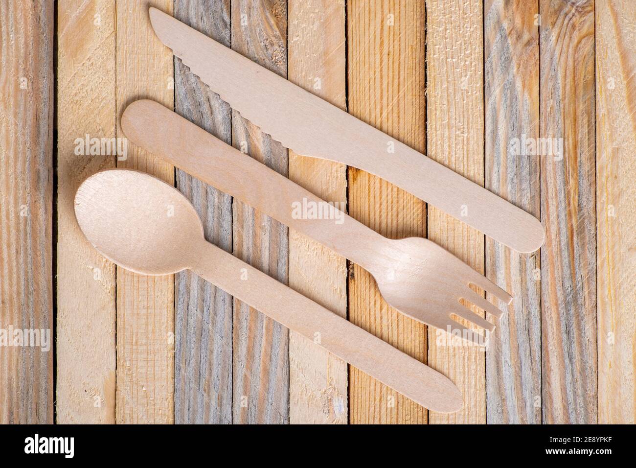 Wooden cutlery stacked on a wooden table. Ecological disposable utensils used at meals. Light background. Stock Photo