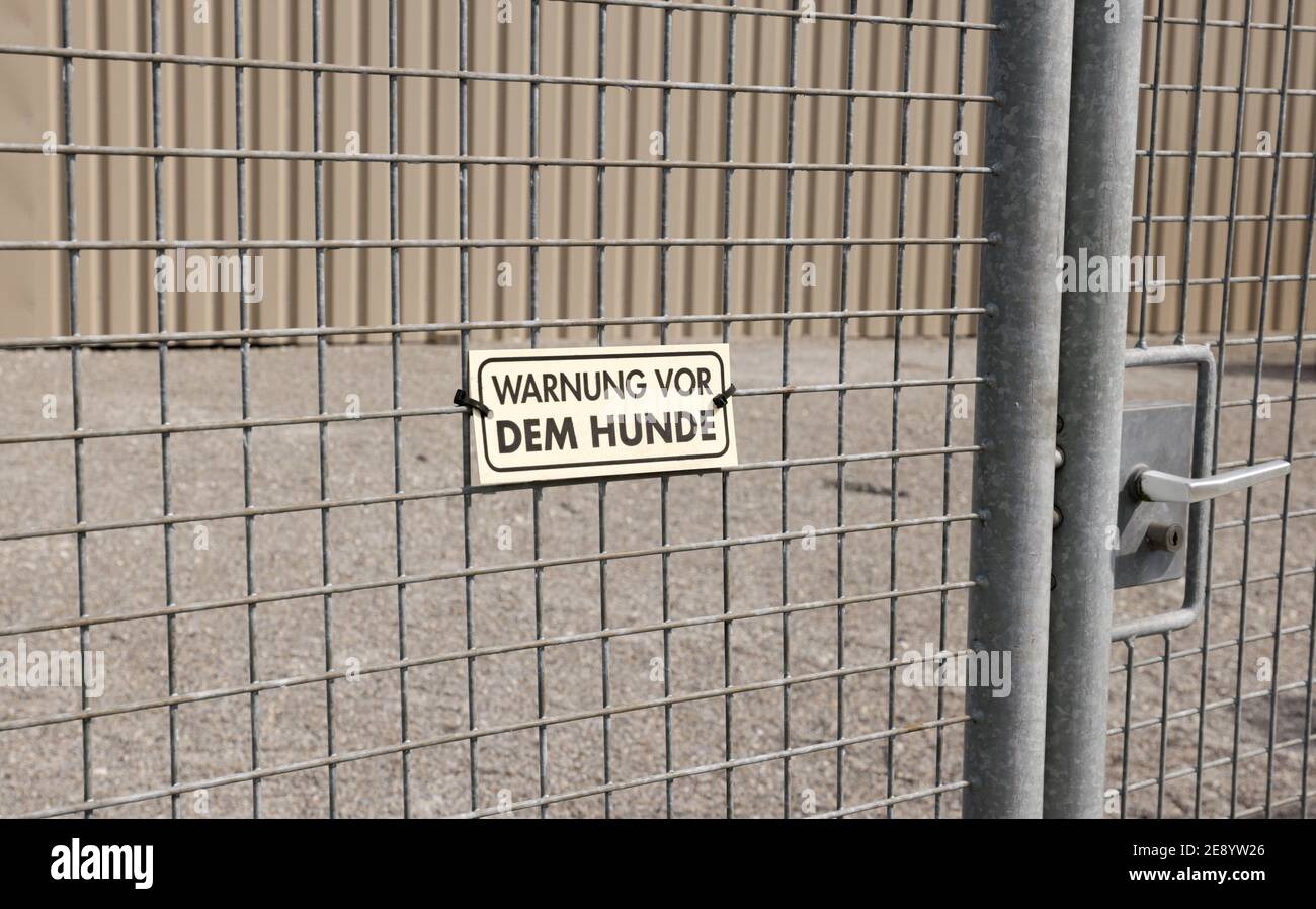 lattice perimeter fence with entrance beware of the dog sign, german text translation: beware of the dog. Stock Photo