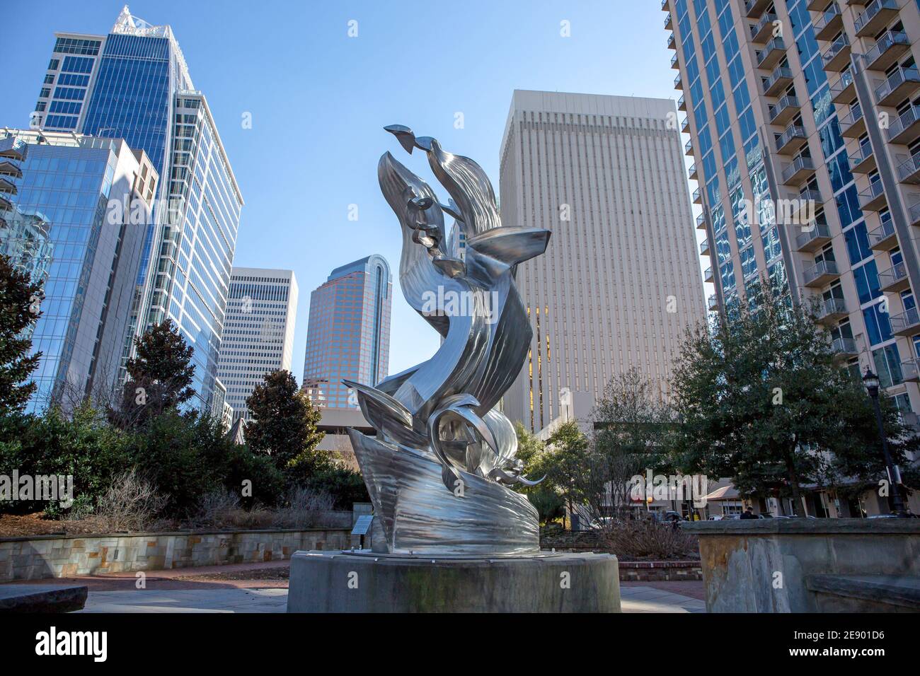 A view of the Charlotte, North Carolina, skyline in a bright blue sky as seen from Romare Bearden Park with modern sculpture. Stock Photo