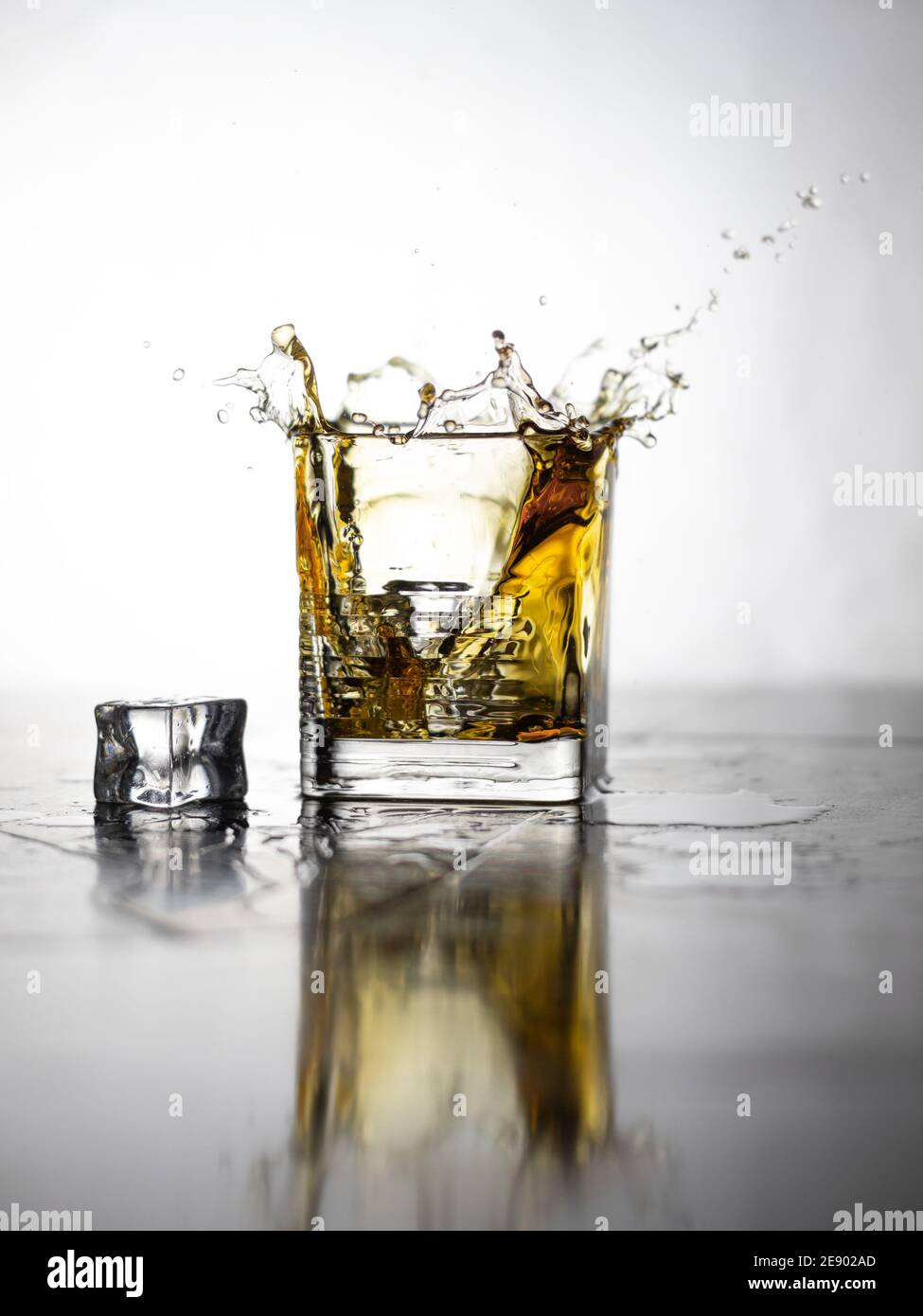 Dropping ice cubes into a whiskey glass. Whiskey splashes Stock Photo