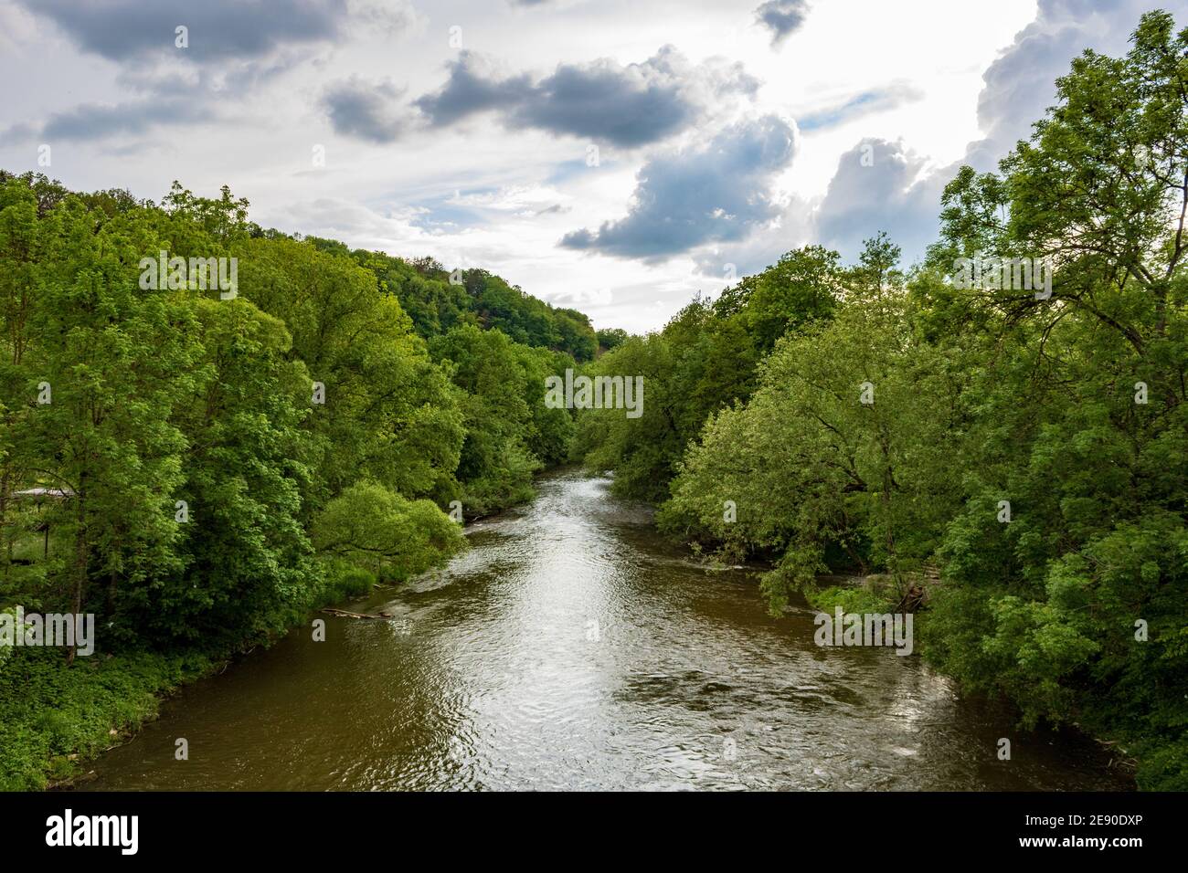 River Jagst flowing between trees with cloudy sky in Neudenau, Germany Stock Photo