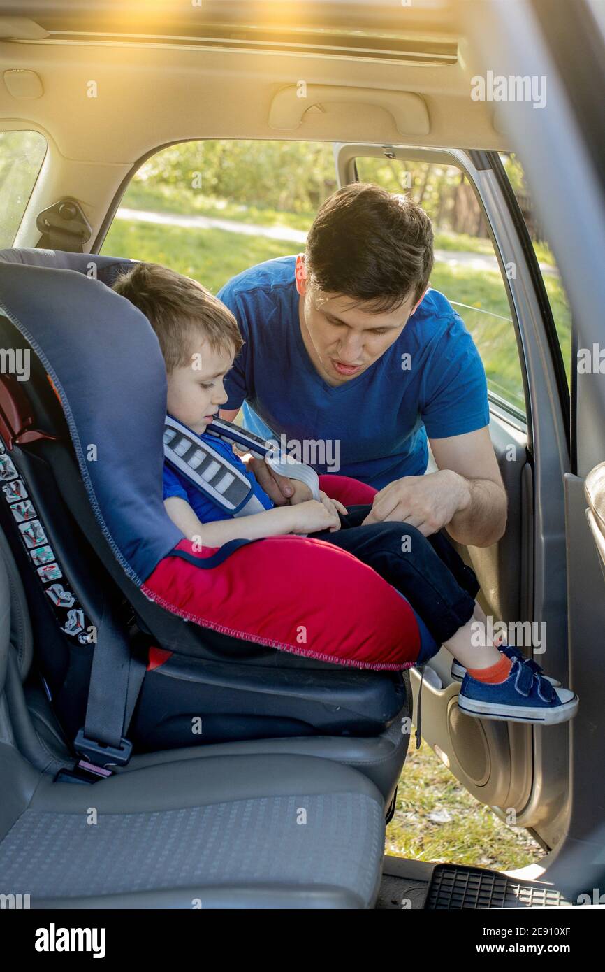 Father putting baby in safety car seat dad and child together family