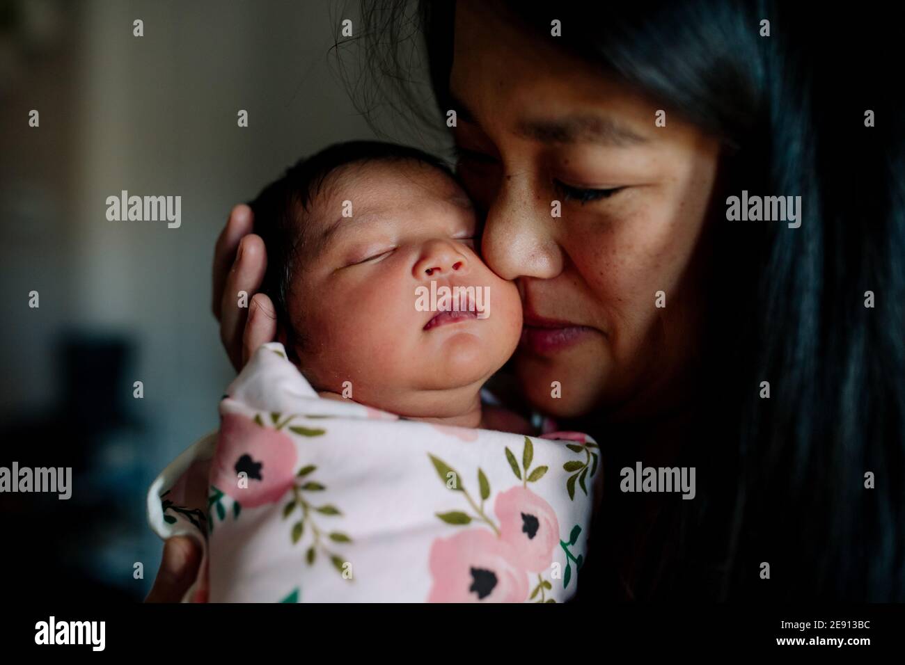 Asian mother tenderly hold newborn baby to her face Stock Photo