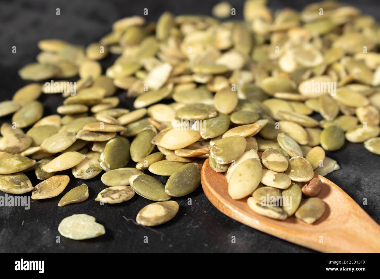 Isolated Stack Of Toasted Hulled Pumpkin Seeds On Black Background Seen From Atop Some Seems Are Displaced Around The Stack Wooden Spoon With Seeds Stock Photo Alamy