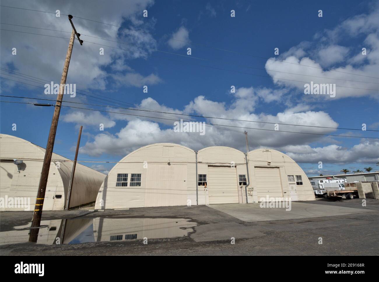 World War 2 medal quonset hut buildings after rain storm, with reflection and sky for copy space, which are now still used for storage after 70 years Stock Photo