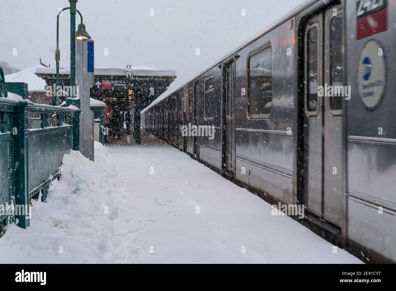 New York, NY - February 1, 2021: View of subway train on elevated above ground station covered with snow as major storm cover New York City with more than a foot expected on the ground Stock Photo