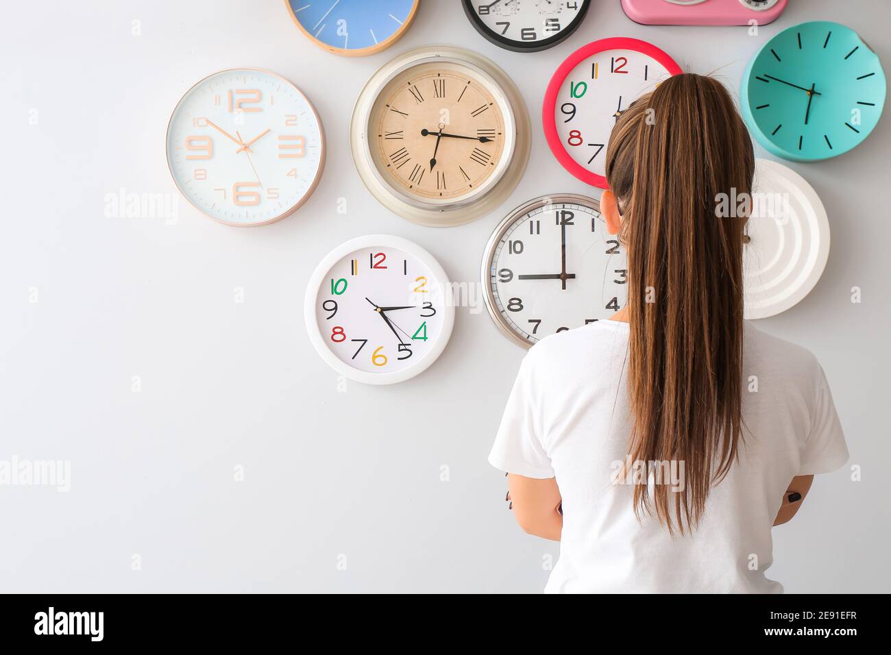 Young woman looking at different clocks Stock Photo Alamy