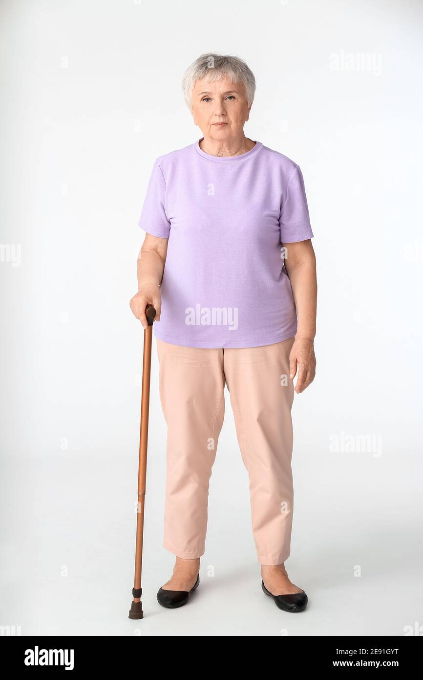 Senior woman with walking stick on white background Stock Photo - Alamy