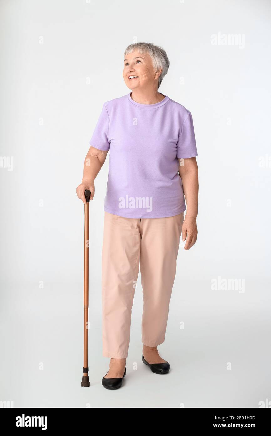 Senior woman with walking stick on white background Stock Photo - Alamy