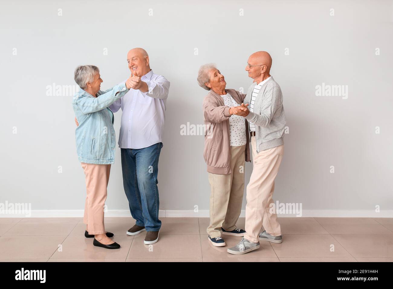 Senior couples dancing near light wall Stock Photo
