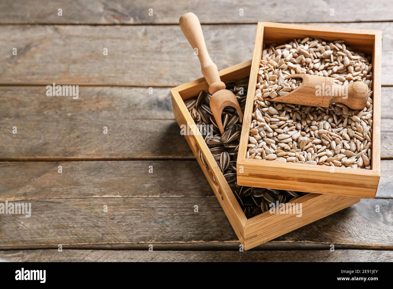 Boxes and scoops with sunflower seeds on wooden background Stock Photo
