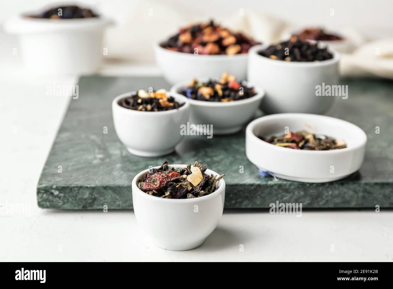 Bowls with different types of dry fruit tea on light background Stock