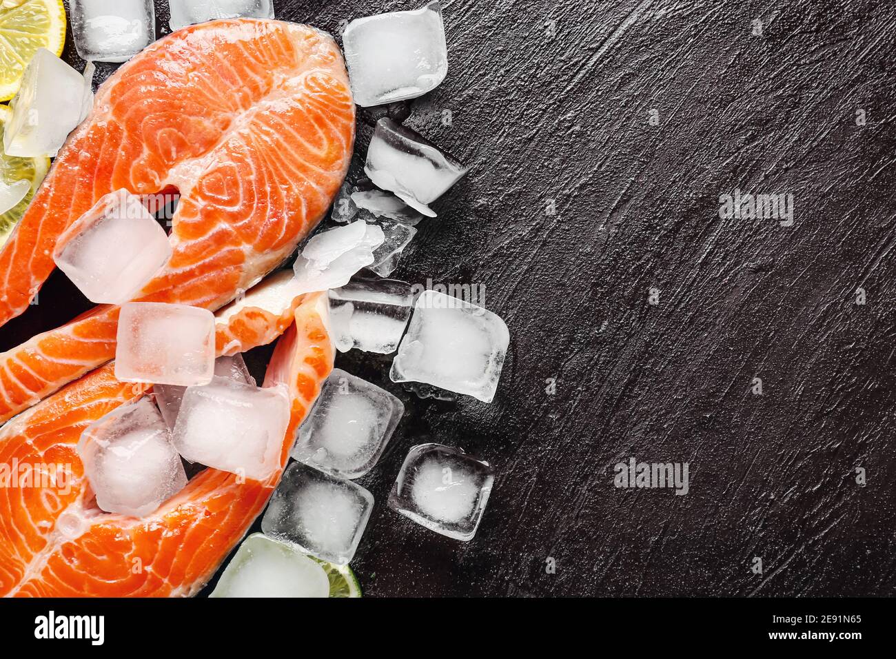Raw salmon steaks, ice cubes and lemon on dark background Stock Photo ...