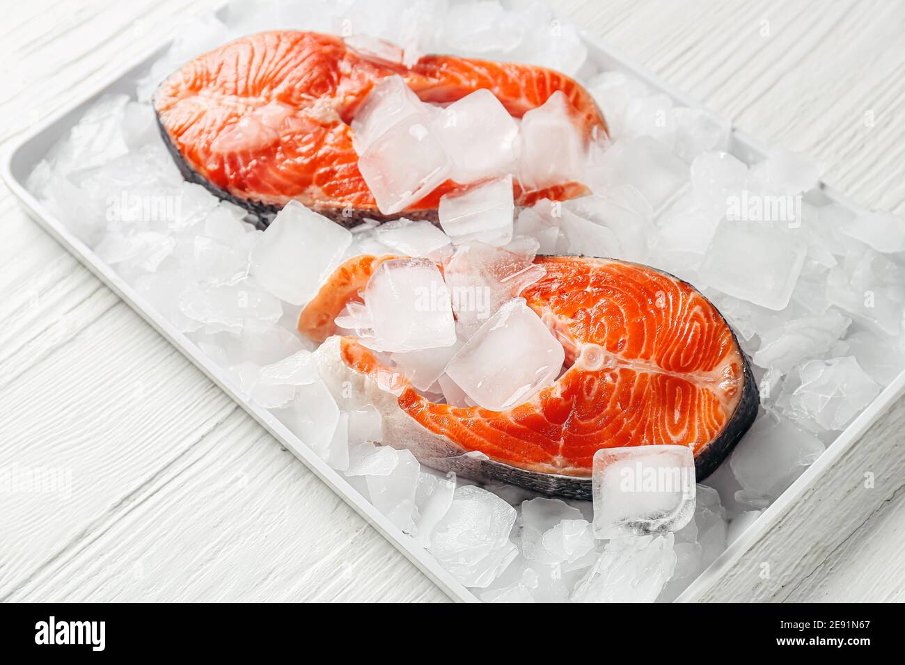 Raw salmon steaks and ice cubes on light background Stock Photo - Alamy